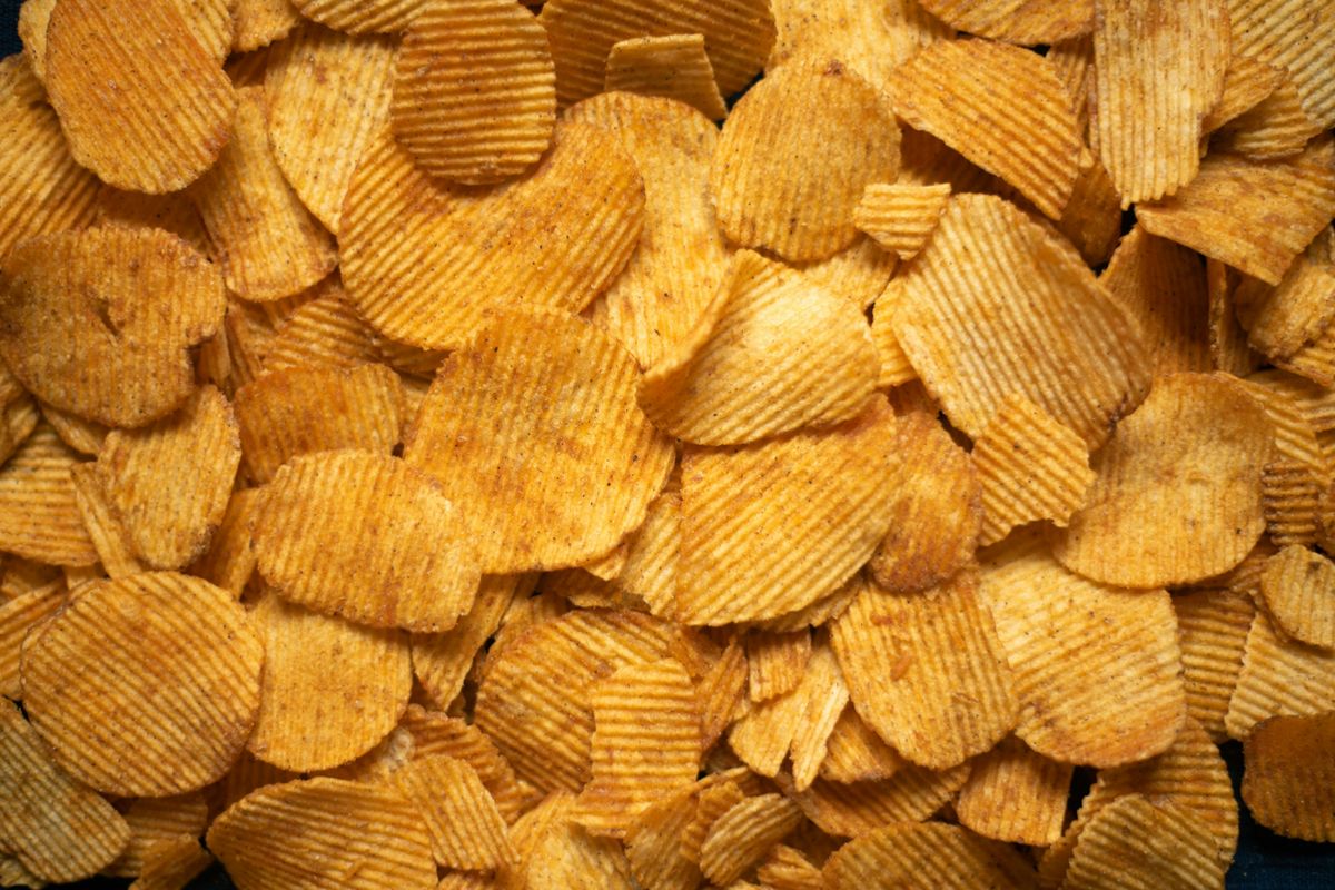 A delicious pile of golden crispy potato chips viewed from above. cover
